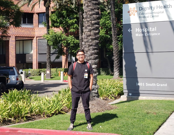 Rene Amel Peralta in front of the Dignity Health sign