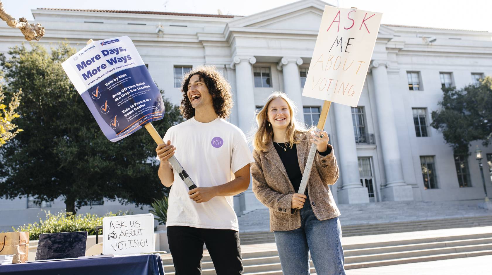 Students Alex Edgar and Skylar Betts hold signs about voting on Sproul Plaza