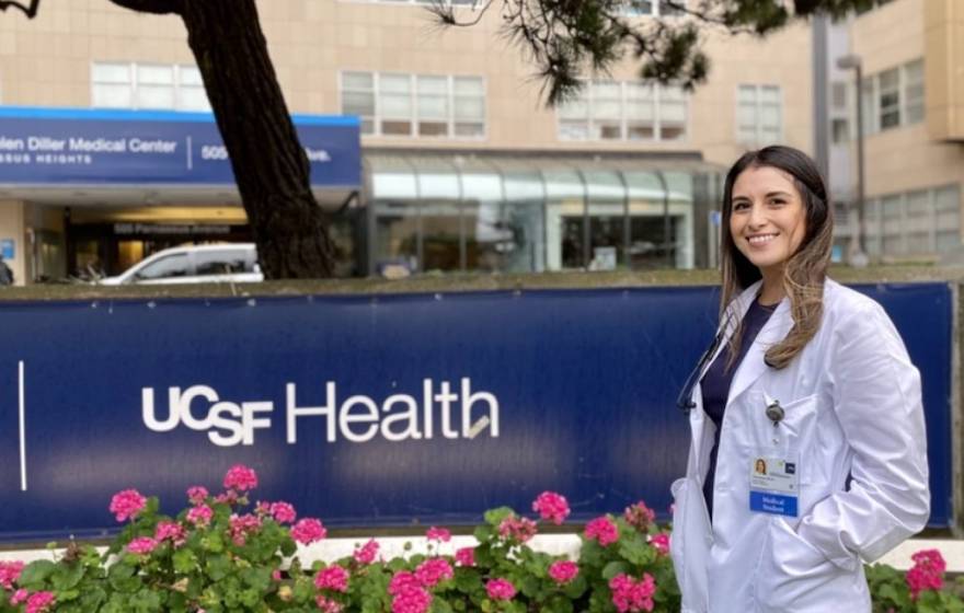 Vanessa Mora in a white coat in front of UCSF Health sign