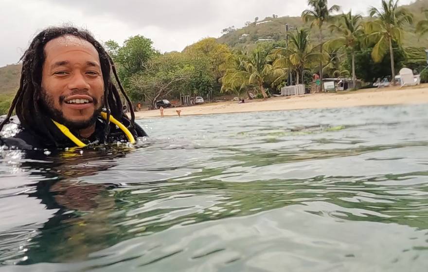 African American man with head poking out of the water, smiling, in scuba gear