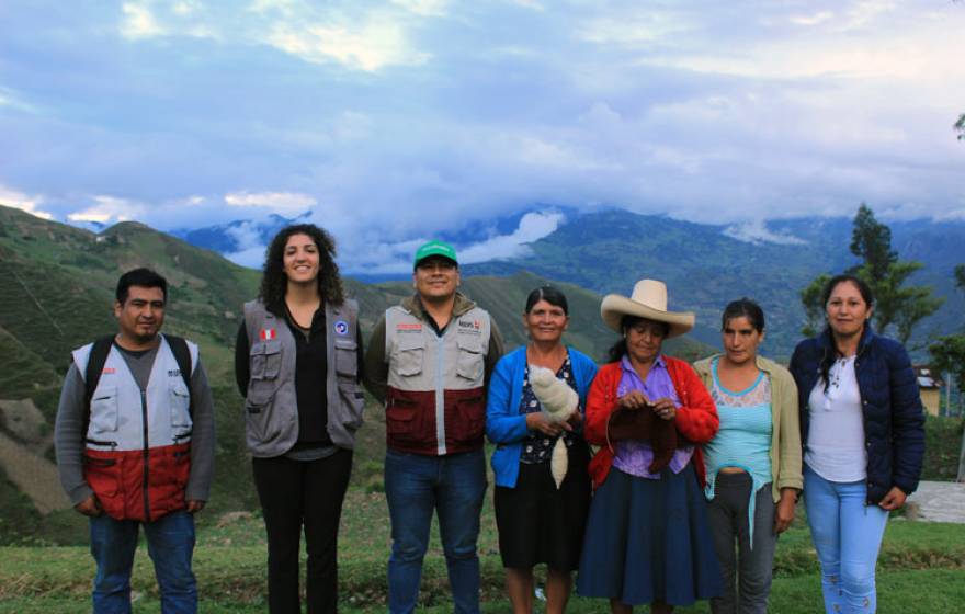 Neeka Mahdavi, a young Iranian-American woman, stands with her hosts in Peru with foggy, cloudy mountains in the background