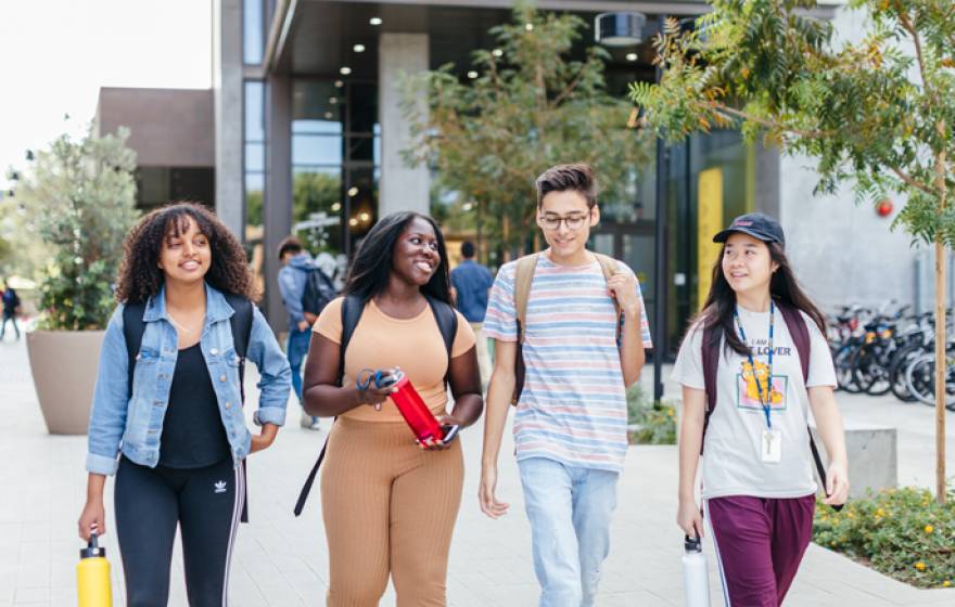Small, diverse group of students walk across the UC Irvine campus