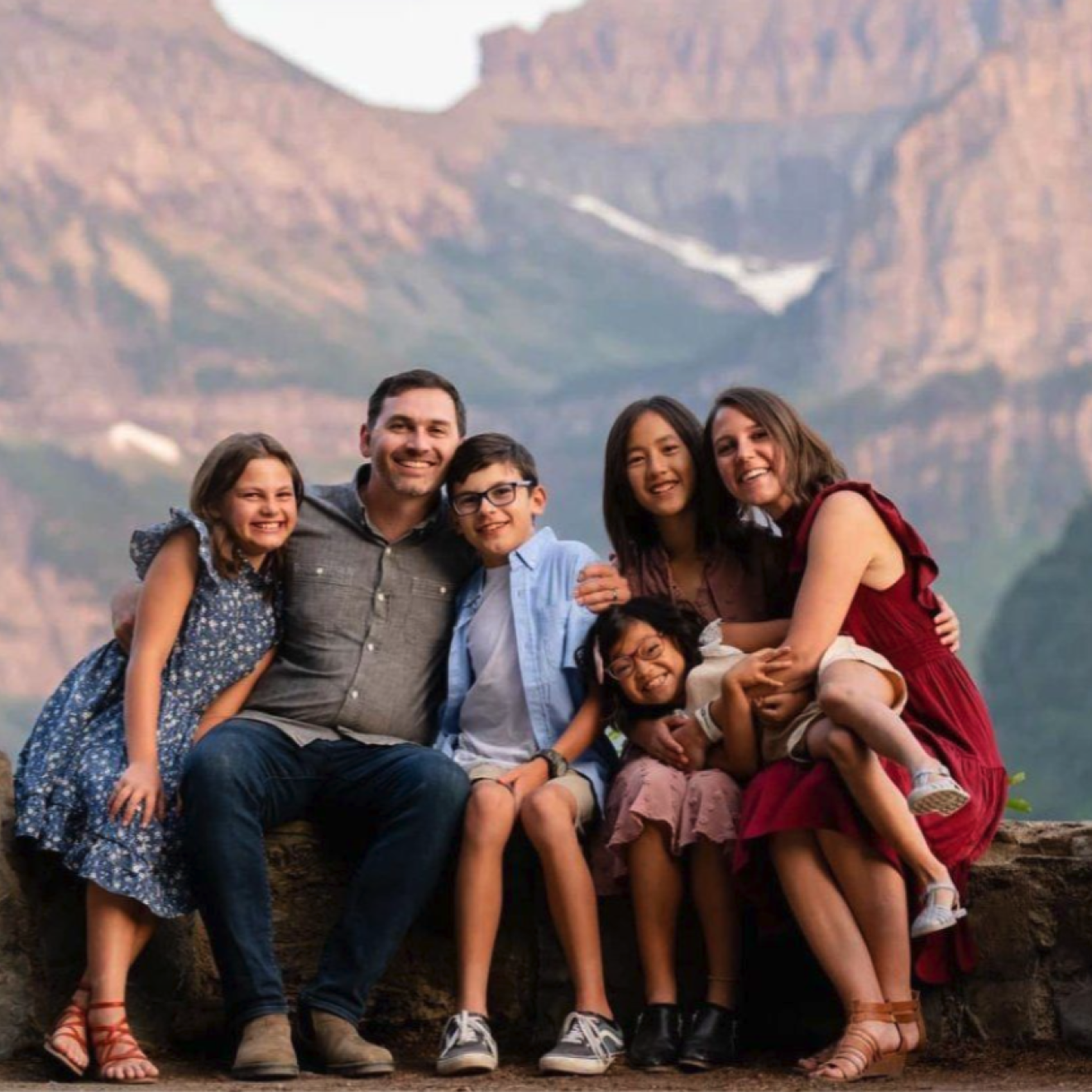 The Finlayson family, a man, woman and 4 kids, poses for a photograph in front of a mountain landscape.