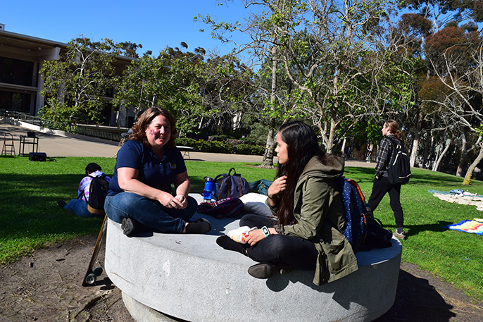 Two students sit on a round concrete bench on campus