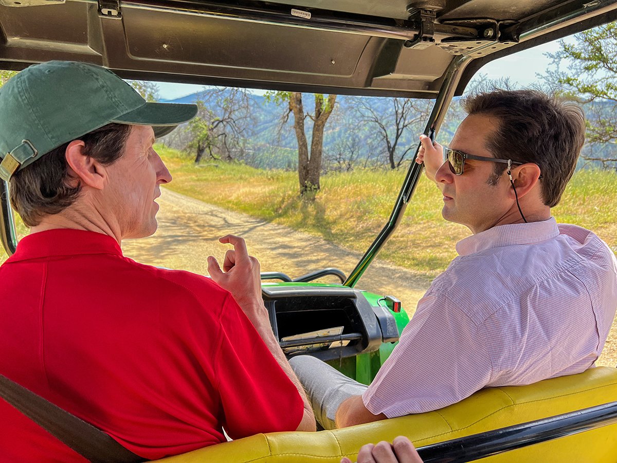 Two men talk in a golf cart on a dirt road in Chile