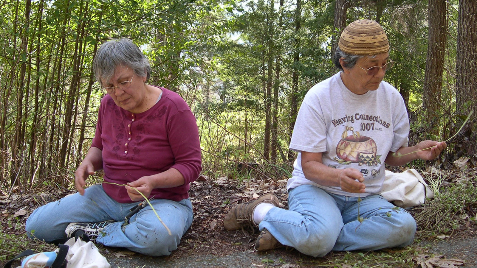 Sisters Lillian Rentz and Janet Morehead of the Karuk Tribe, seated, look at hazel stems
