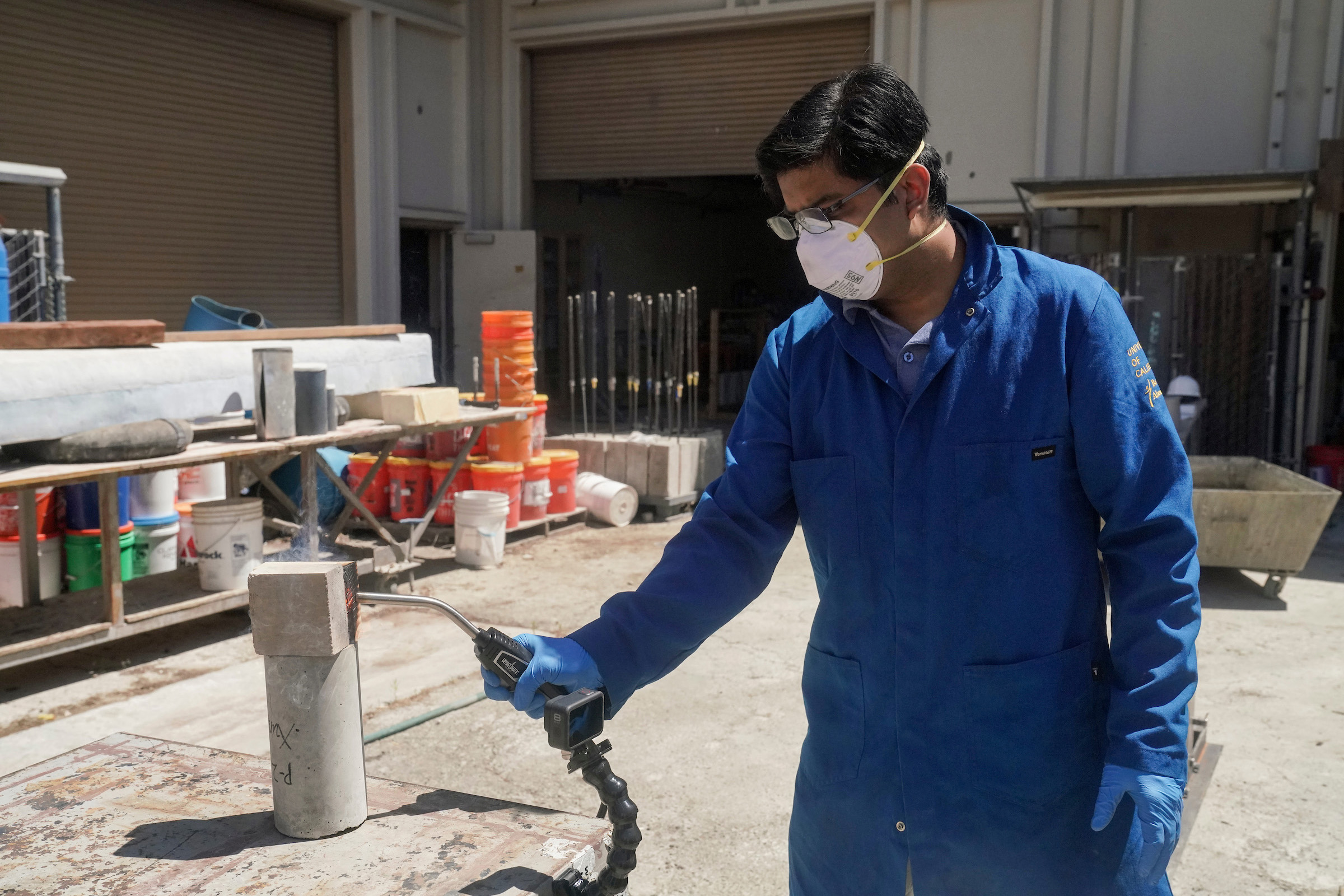 Man in PPE holds blowtorch to earth block