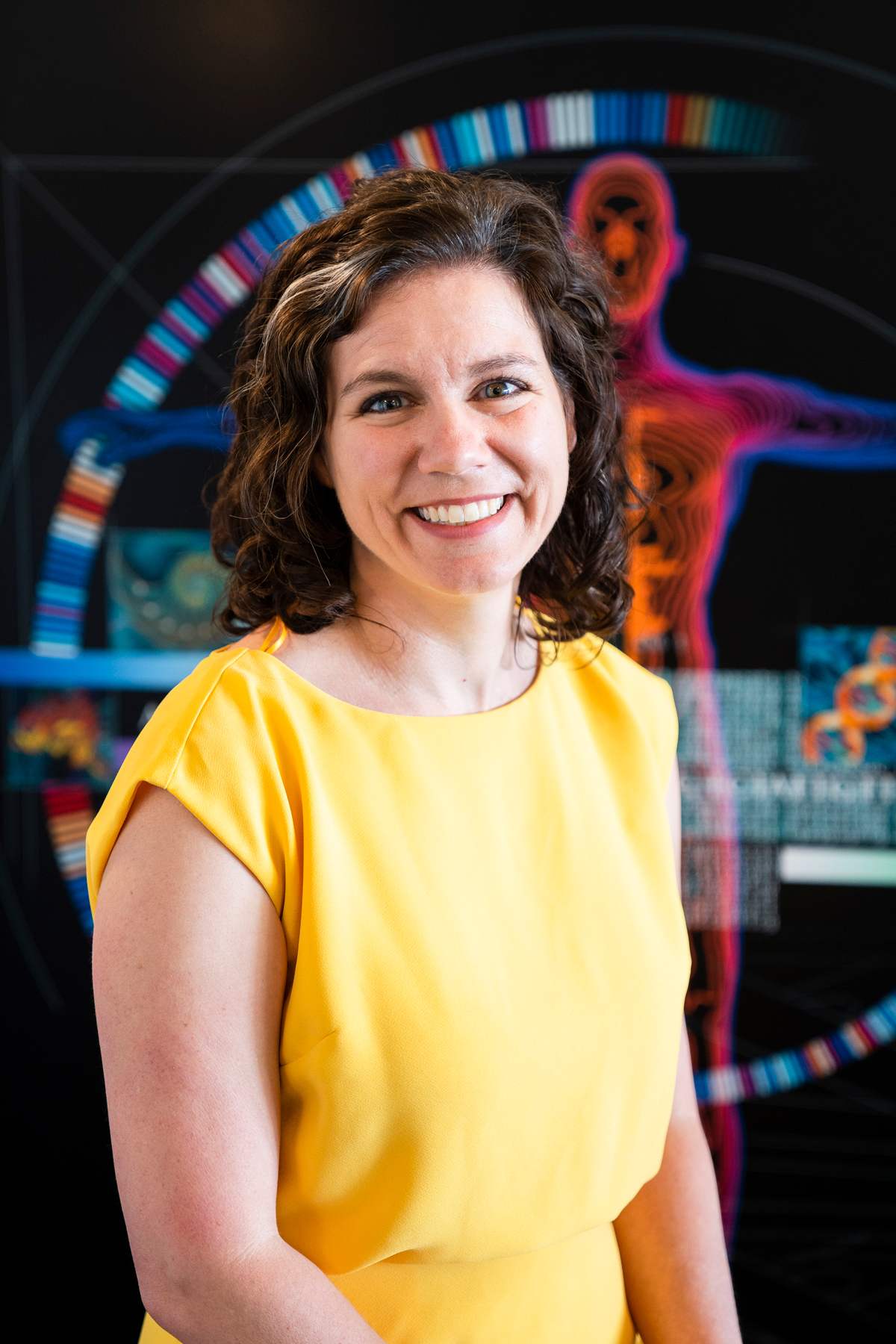 Karen Miga in front of a genome artistic depiction in the background