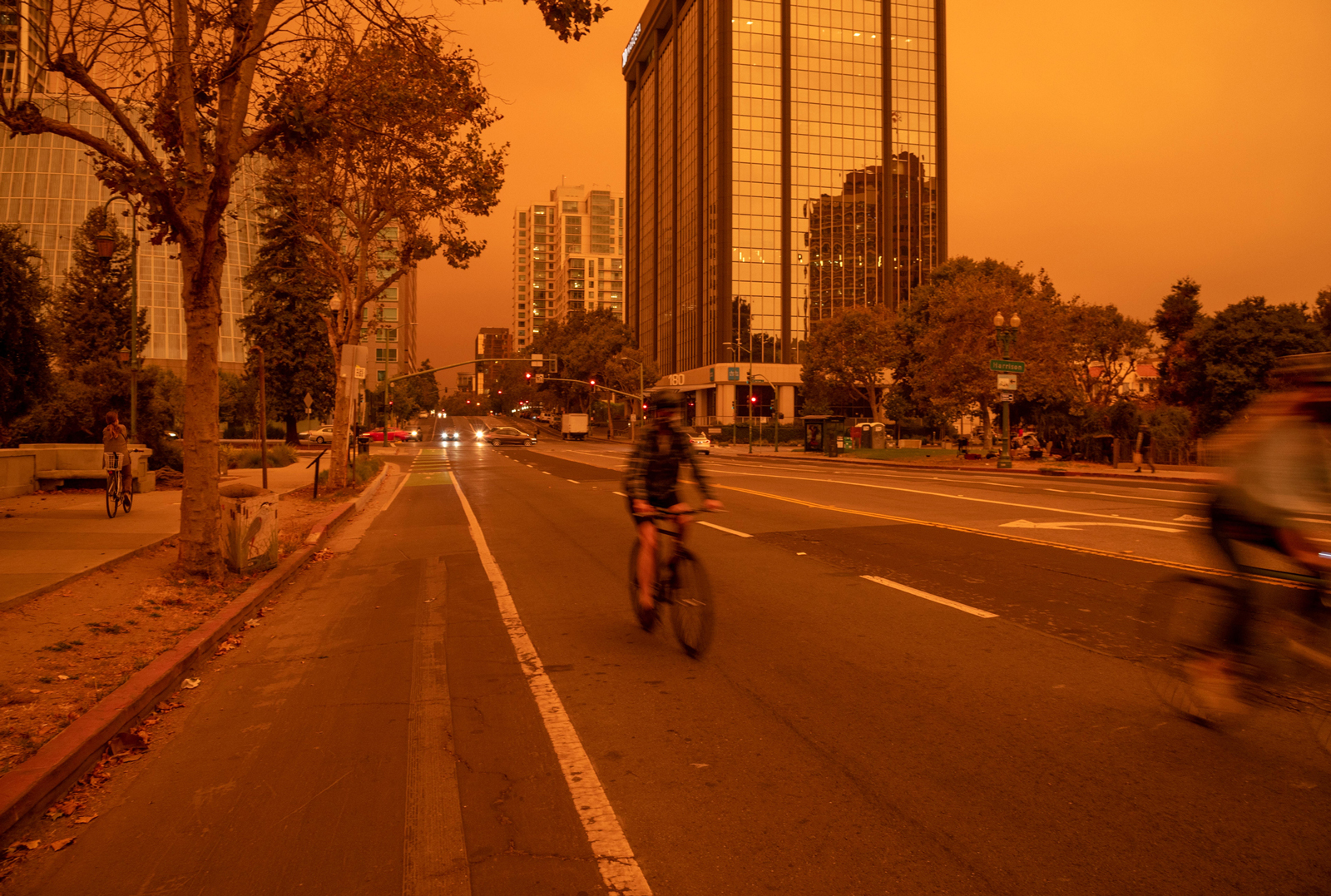 Orange sky over downtown Oakland as people cycle