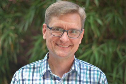 man wearing glasses, trees in background