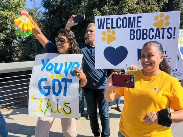 Happy parents holding signs and smiling taking photos of the incoming students