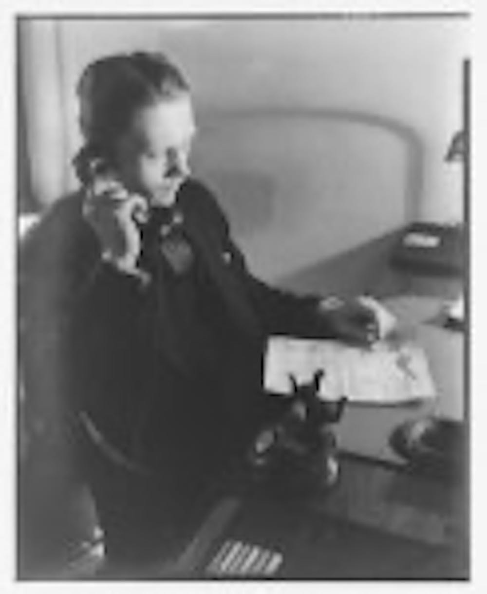 A black and white photograph of a man on an early telephone