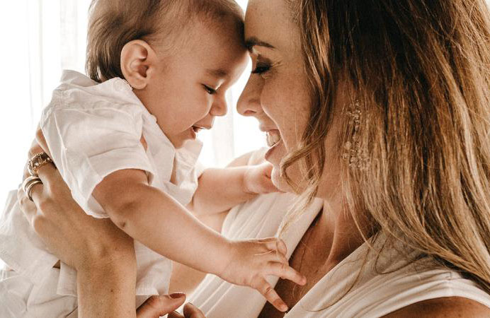 A mother holds her baby, smiling