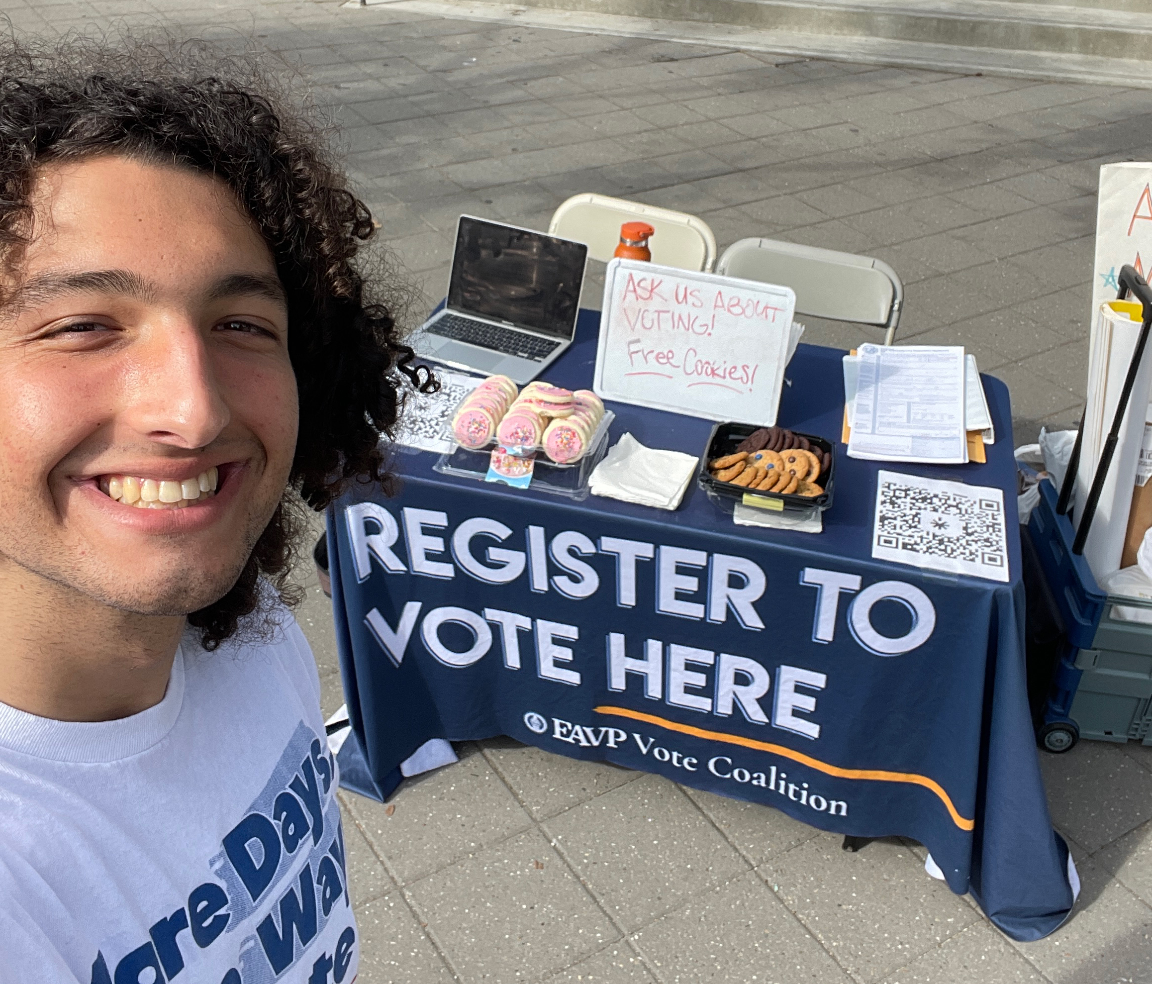 Alex Edgar does a selfie while in front of a voter registration table