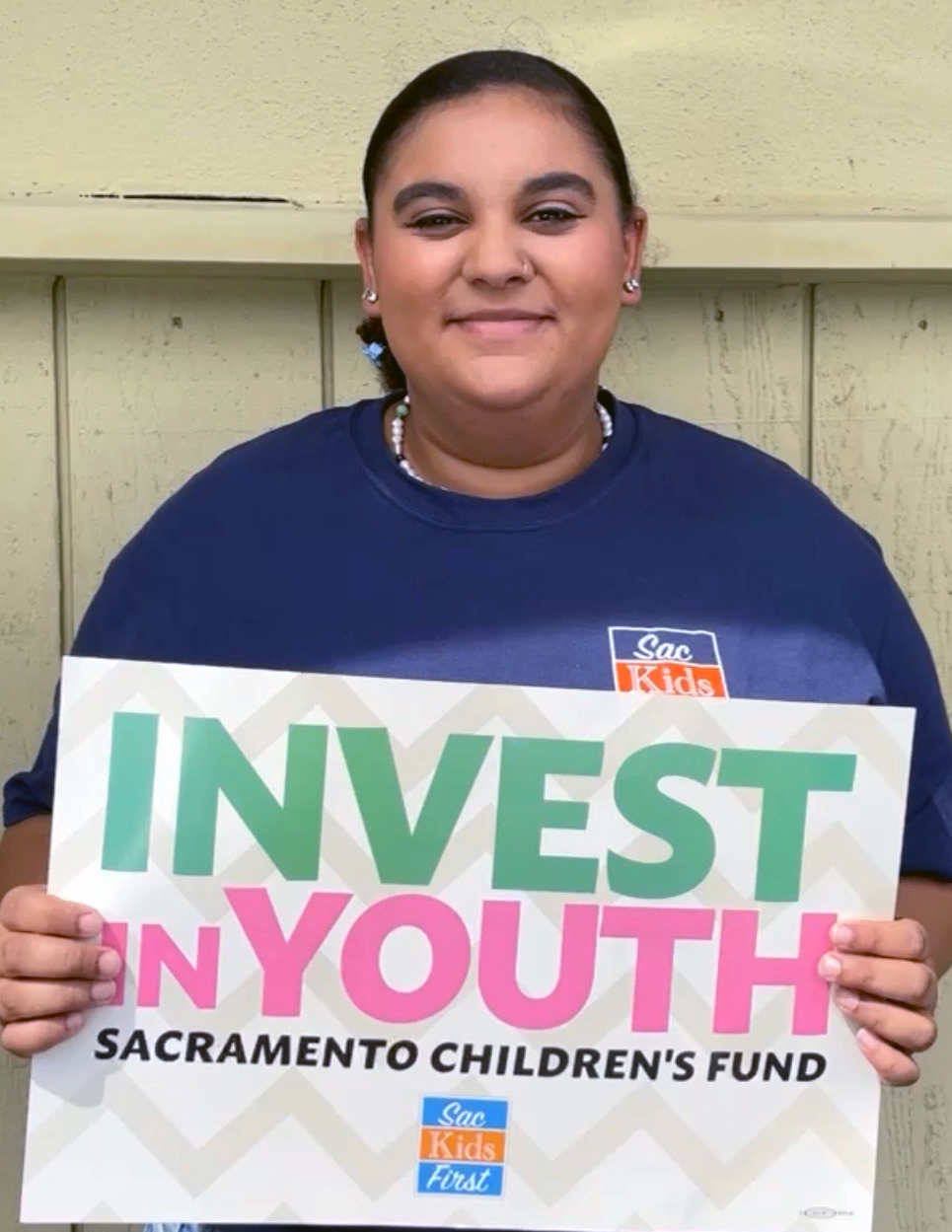 Kennedy McIntyre holding an "Invest in Youth" poster
