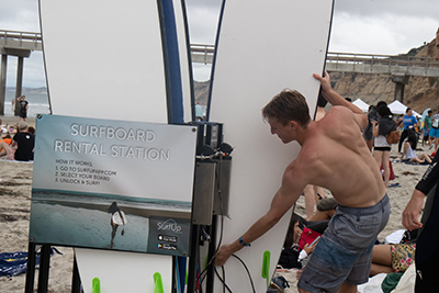 A man lifting a surfboard off a rack