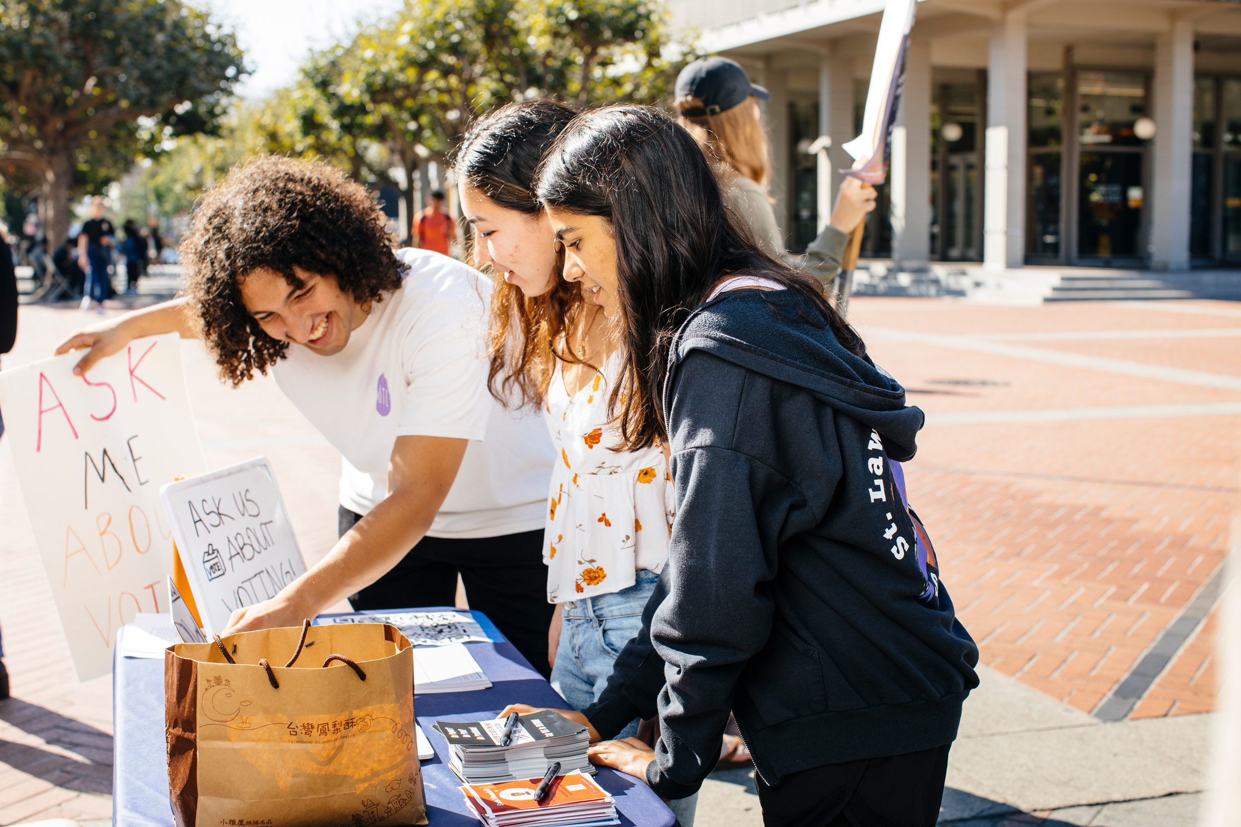 Alex Edgar answers the questions of two young women at a voter registration table