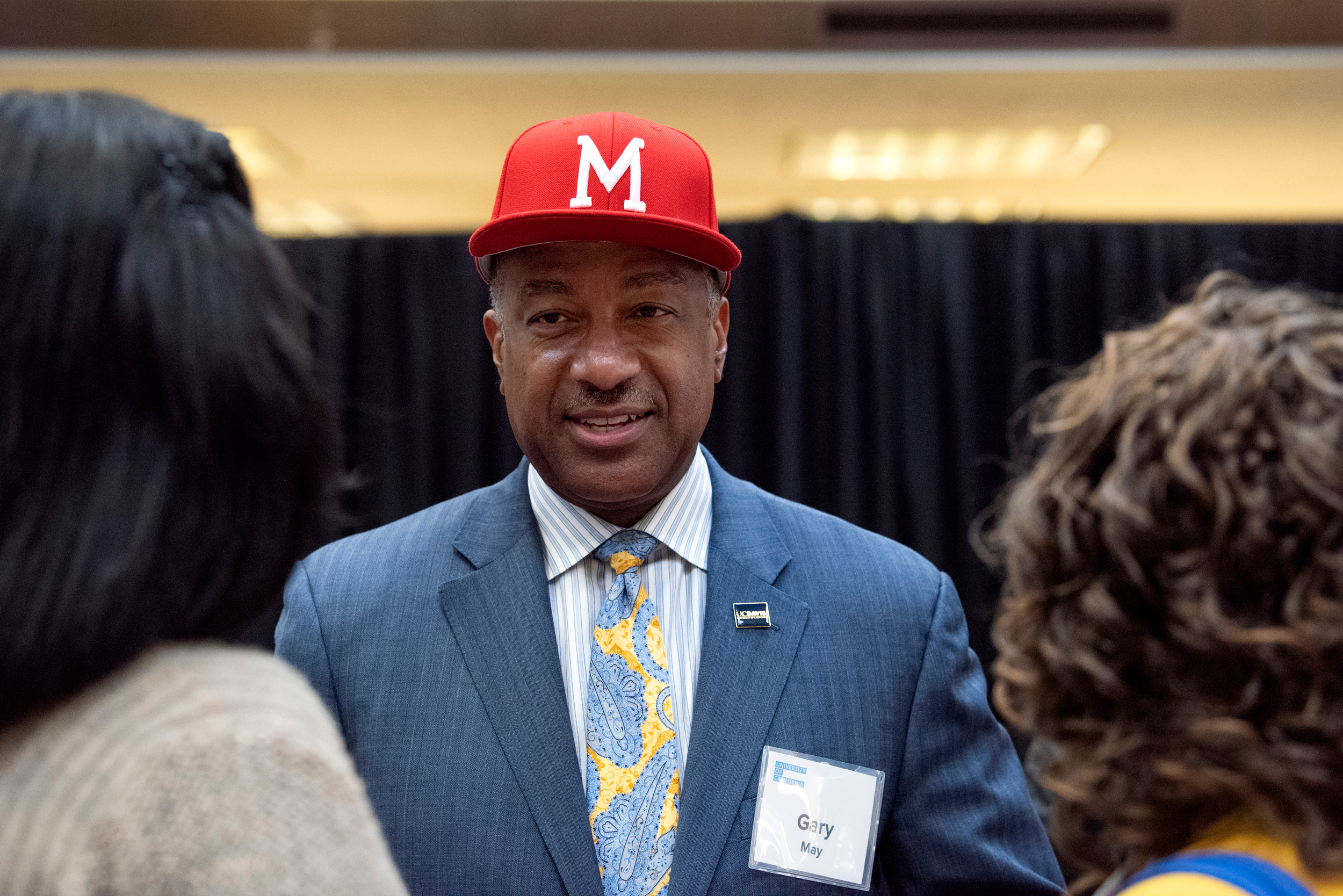 Gary May in M ballcap talking to two people