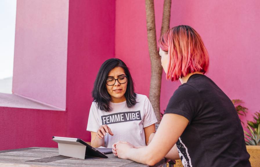 A person wearing a 'Femme vibe' shirt talks to another person