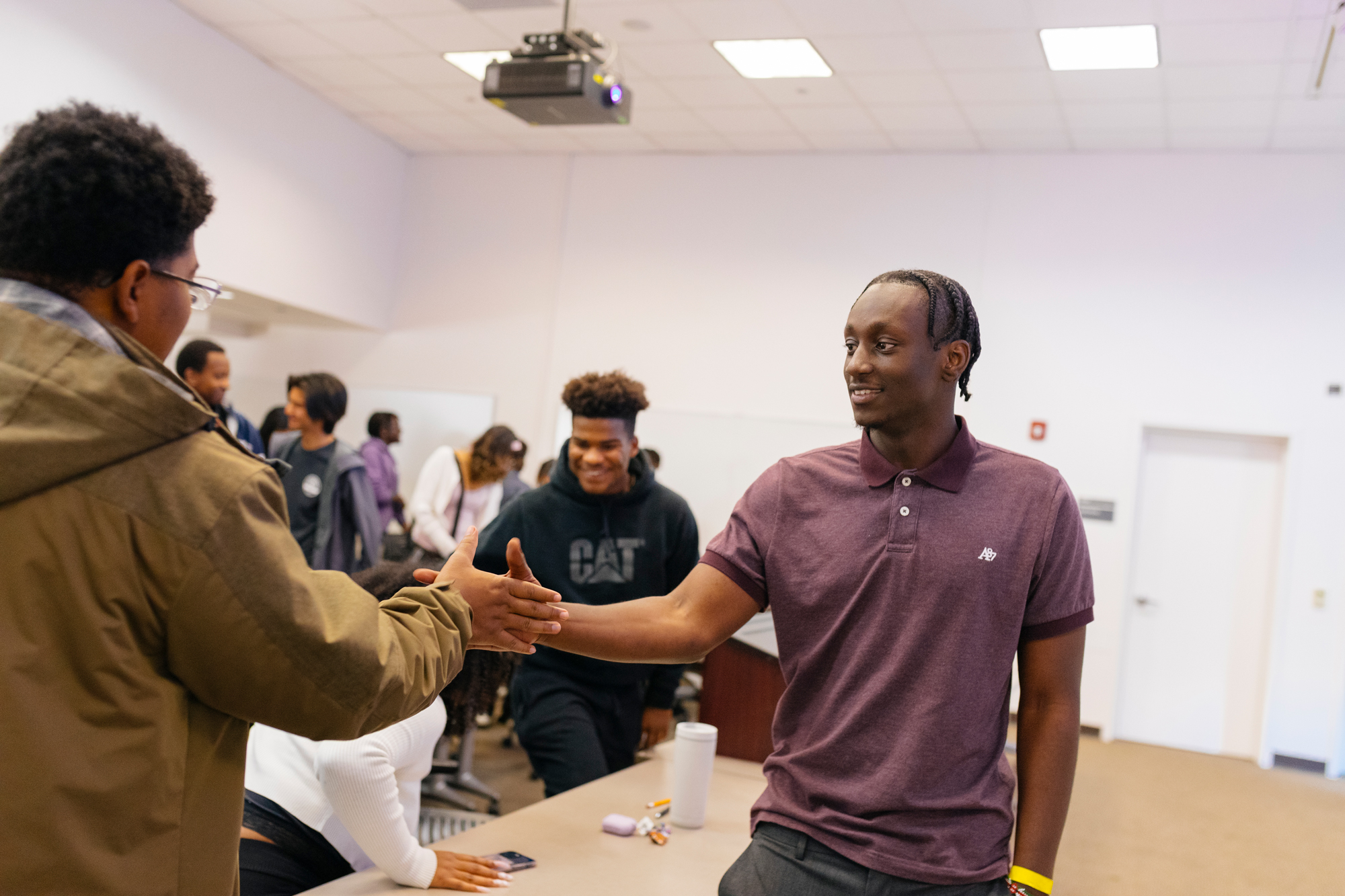 Nduati Macharia shakes hands with a teen student in a classroom