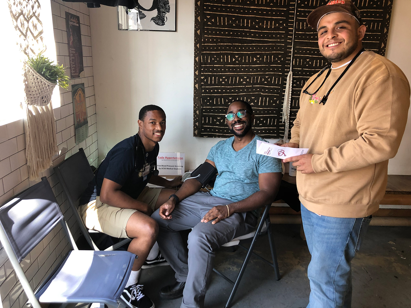 Edgar Vega, right, at a barbershop with two young men to the left