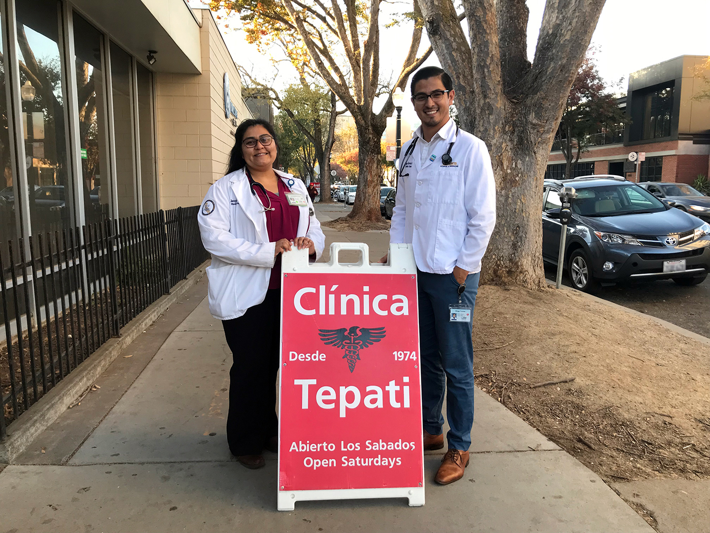 Jacqueline A. León, left, with another doctor, flanking an advertisement for the UC Davis Clínica Tepati