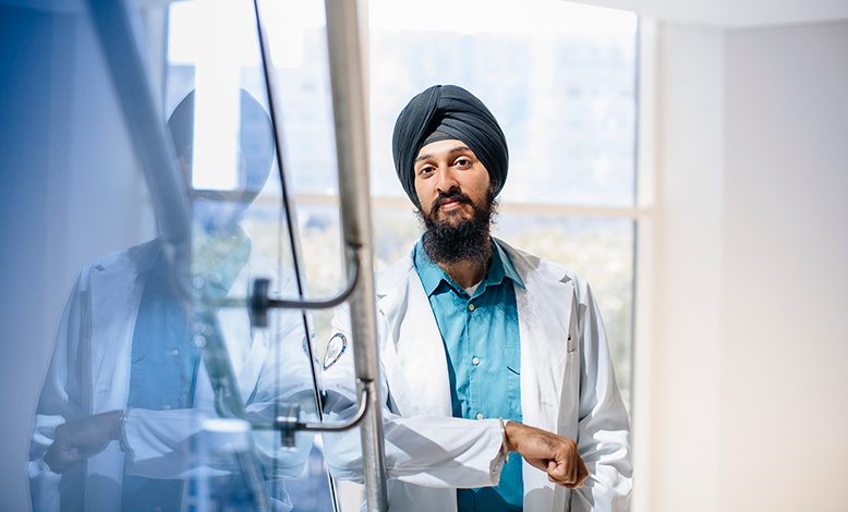 A Sikh doctor resting against a handrail on the stairs