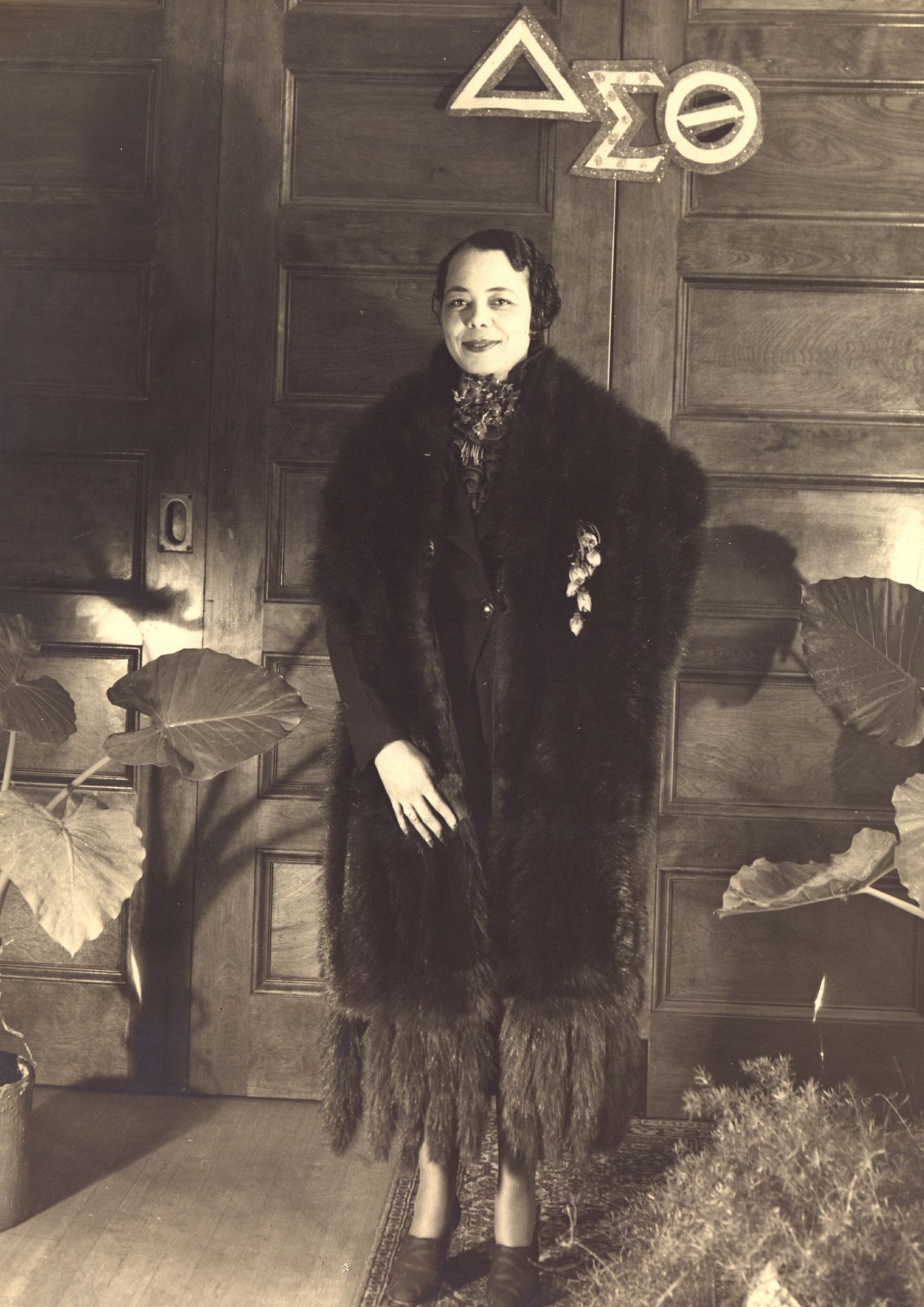 An old photograph of a woman in a fur coat in a Black sorority house