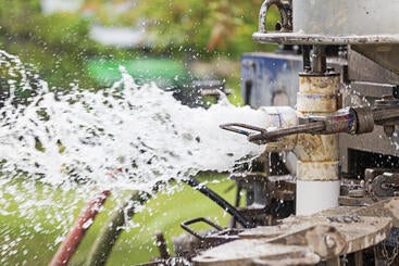 Water spraying out while a drill is drilling a well