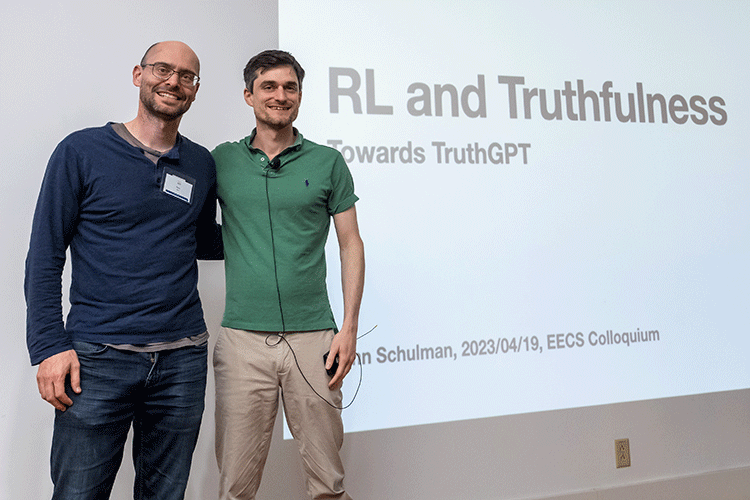 Schulman with his Ph.D. advisor Pieter Abbeel in front of a projected screen