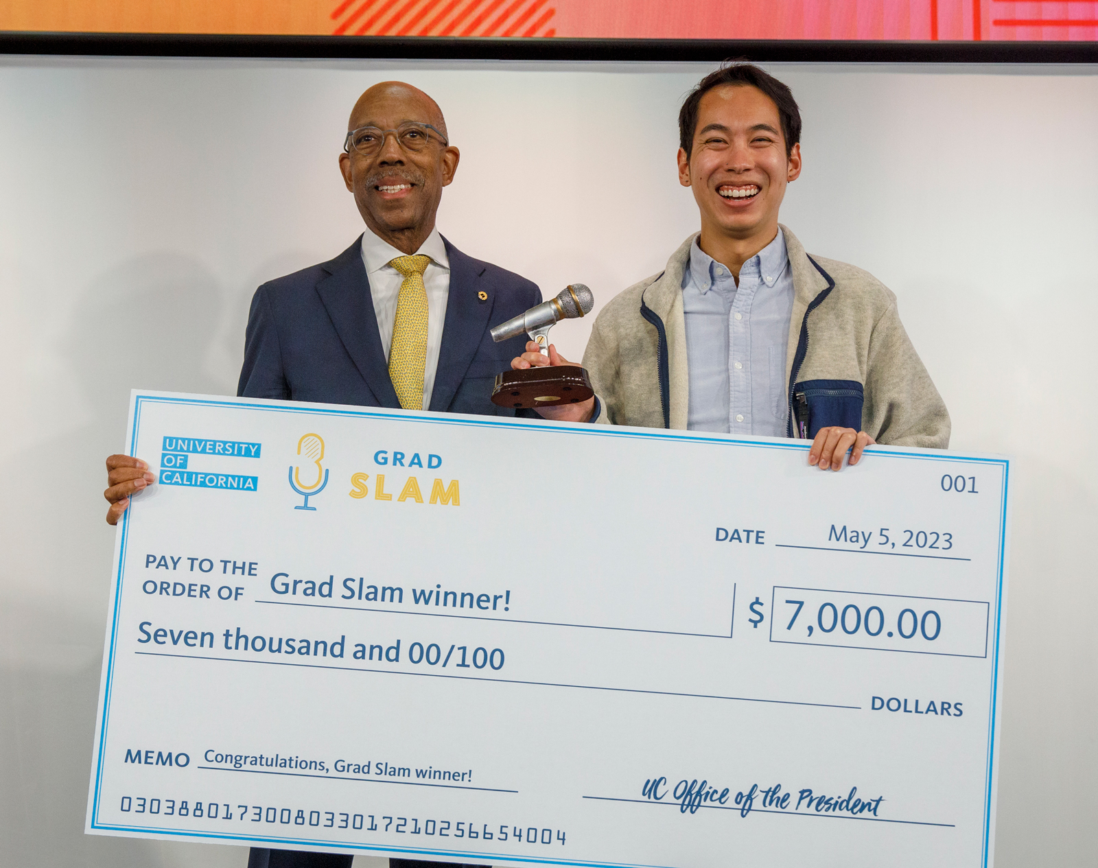 Brandon Tsai stands next to UC President Michael V. Drake, M.D., with his giant check