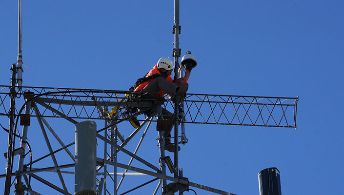 Person installing a camera, blue sky behind