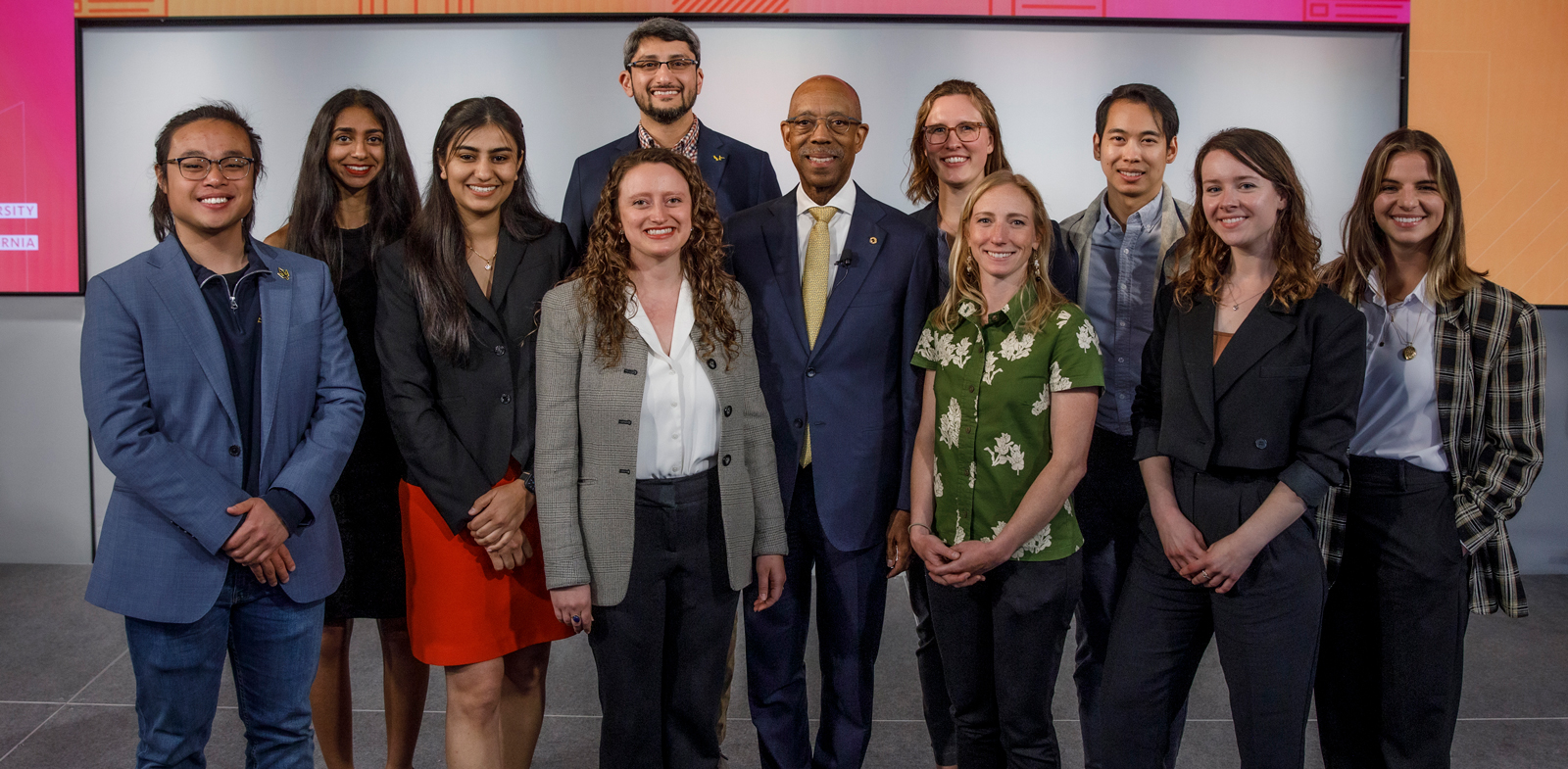 All 10 UC Grad Slam contestants in a group photo on the bright LinkedIn stage with President Michael V. Drake