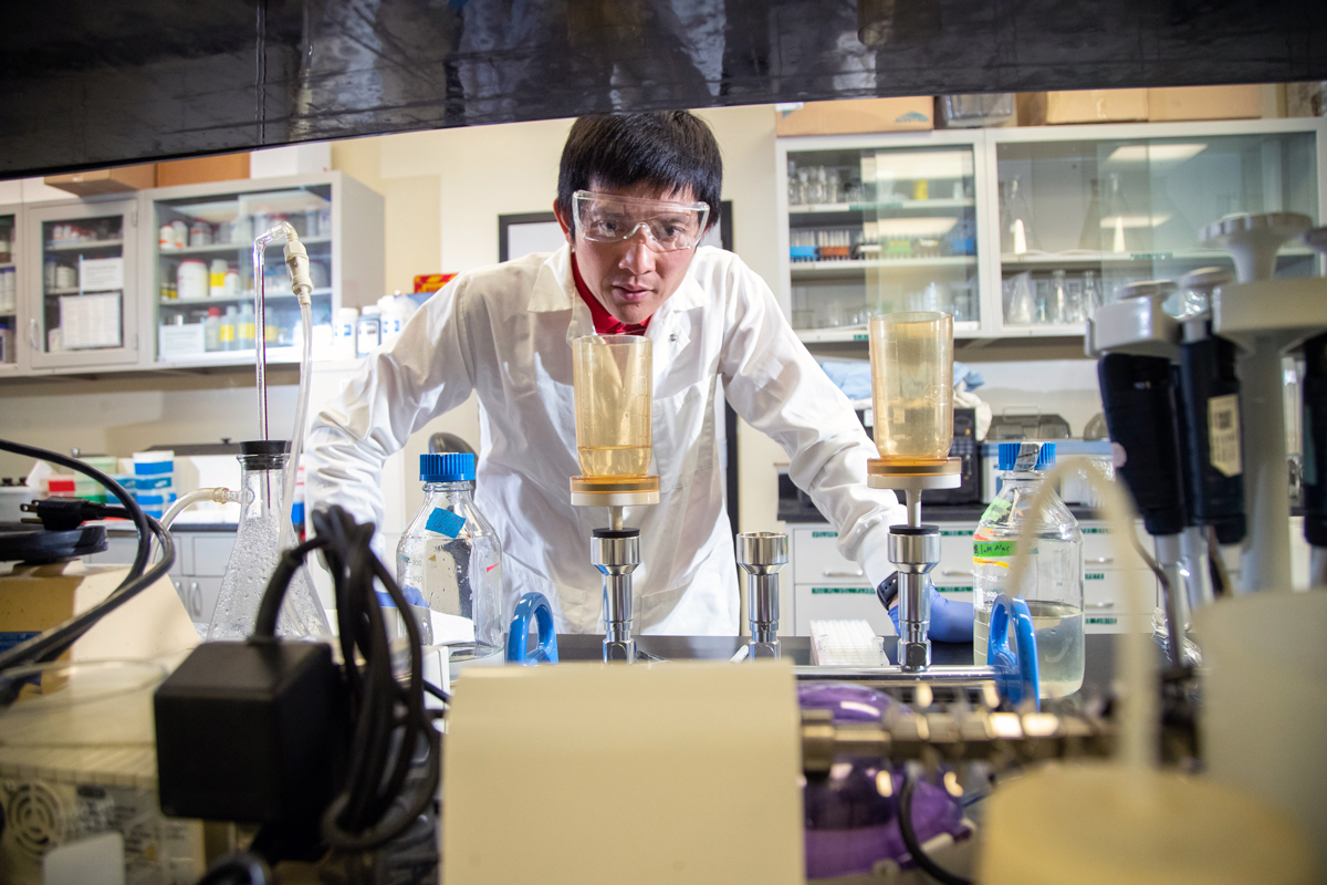 A  young Asian man wearing safety googles and gear testing water in the lab
