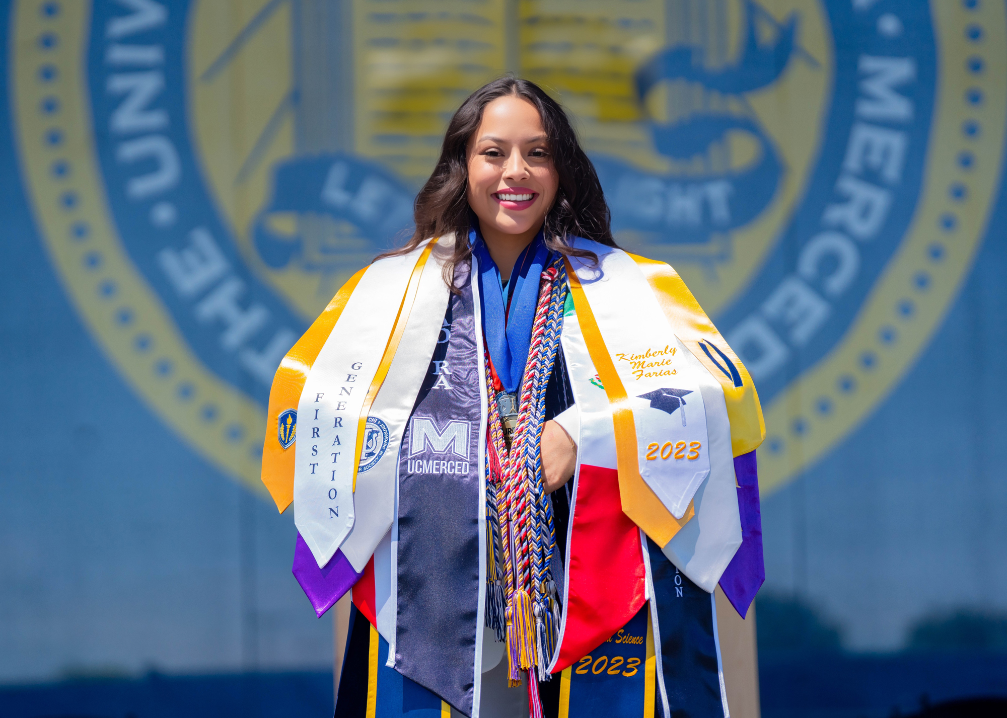 Kimberly Farias in her graduation gown with several stoles