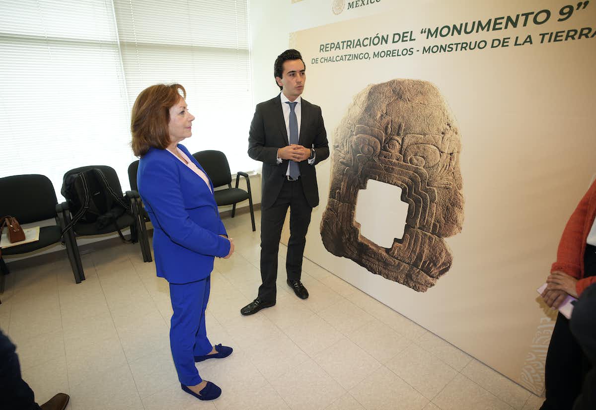 Colorado Lt. Gov. Dianne Primavera, left, is shown a photograph of Monument 9 by a man in a suit before it was returned to Mexico. 