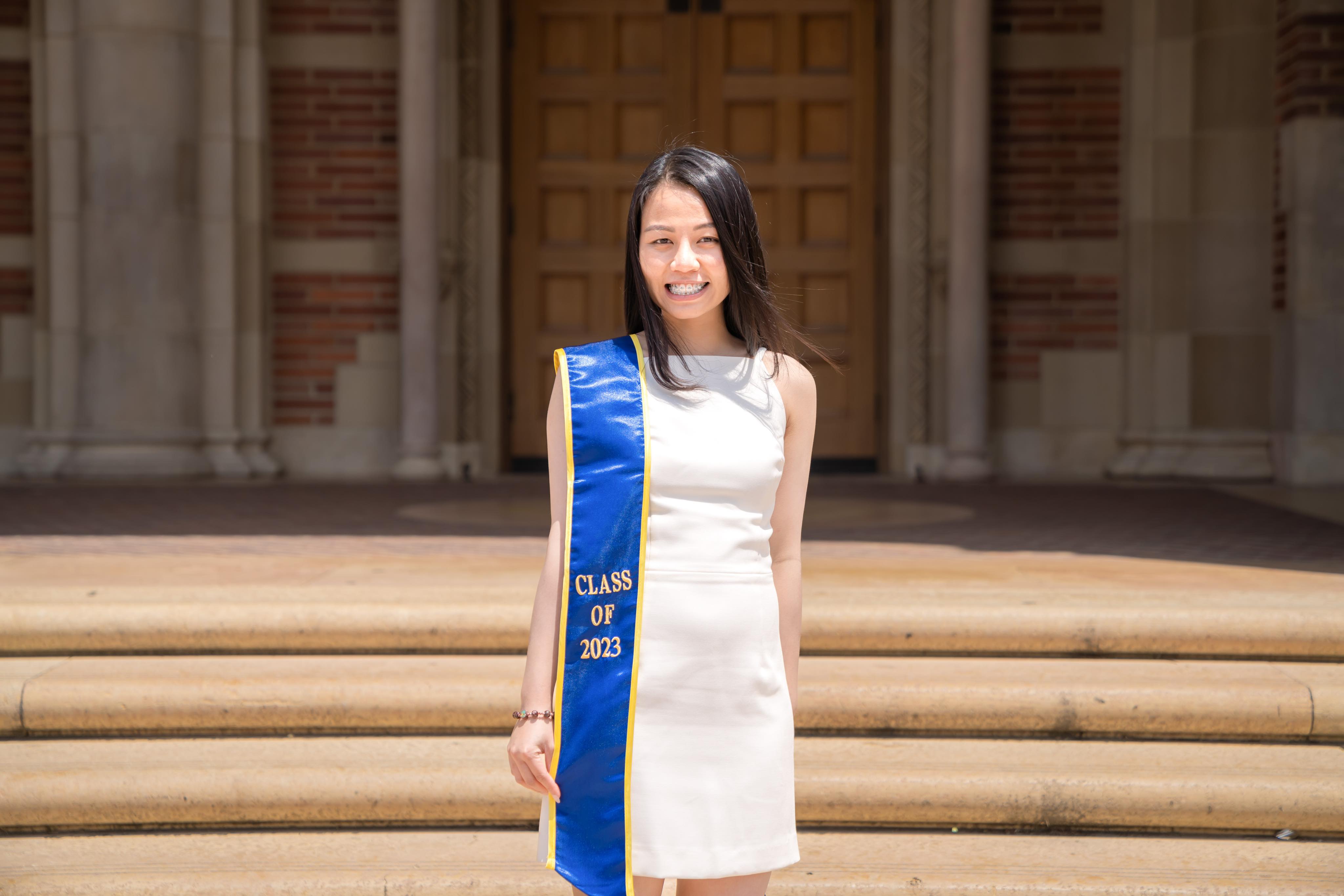 Thien Nguyen with a graduation sash on the steps