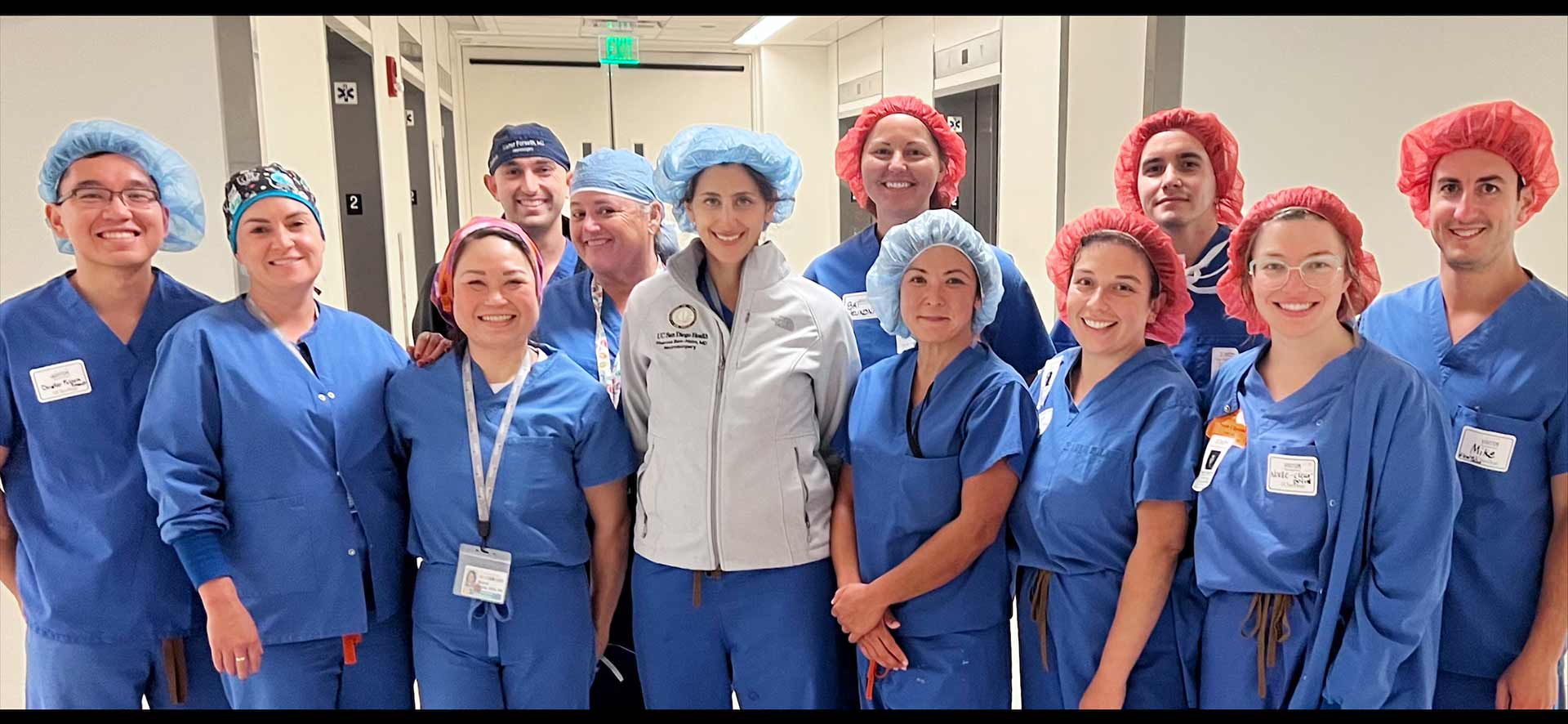 A group of surgeons standing together in a hallway, smiling