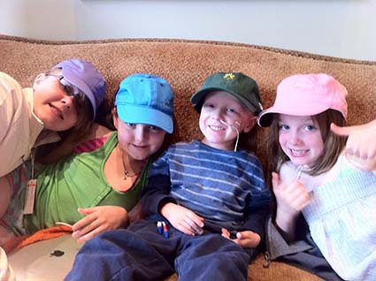 Four kids in ballcaps on a couch