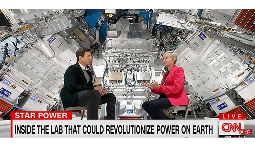 A man talking to Secretary Granholm with a backdrop of the lab on CNN