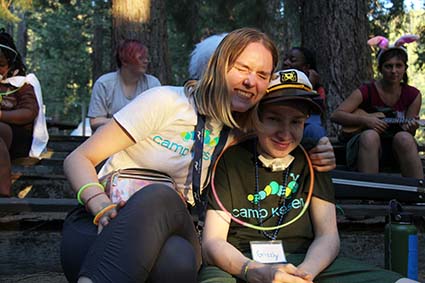 A young woman holds her brother in the redwoods at Camp Kesem