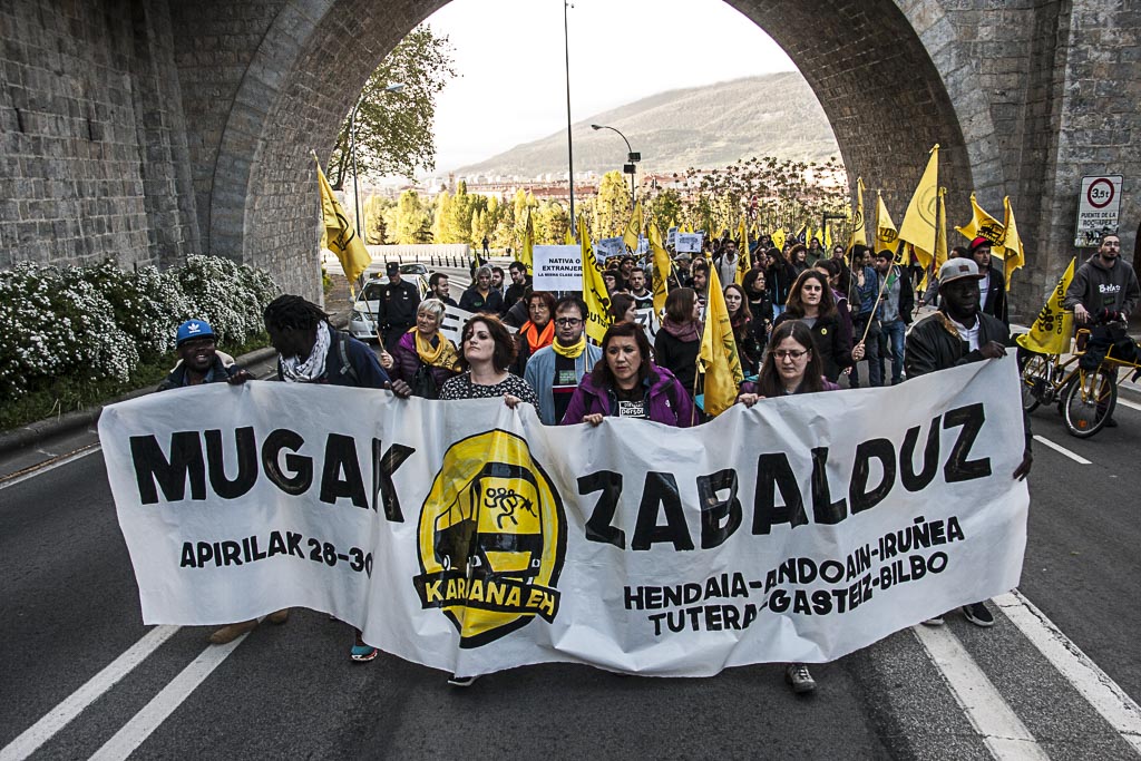 People in Pamplona marching behind a banner in Basque supporting refugees