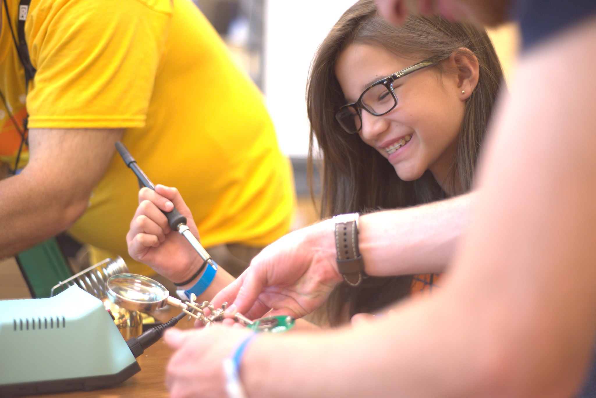 A smiling young Asian pre-teen works on a mechanical project