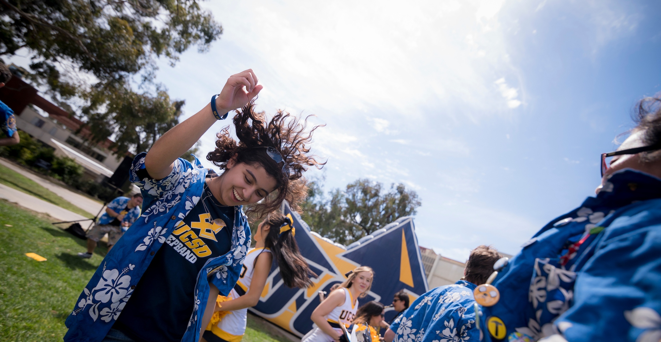 A student in a Hawaiian shirt dancing among other students