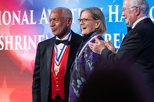 Kathryn Sullivan smiles on stage wearing a medal with other Hall of Fame inductees.