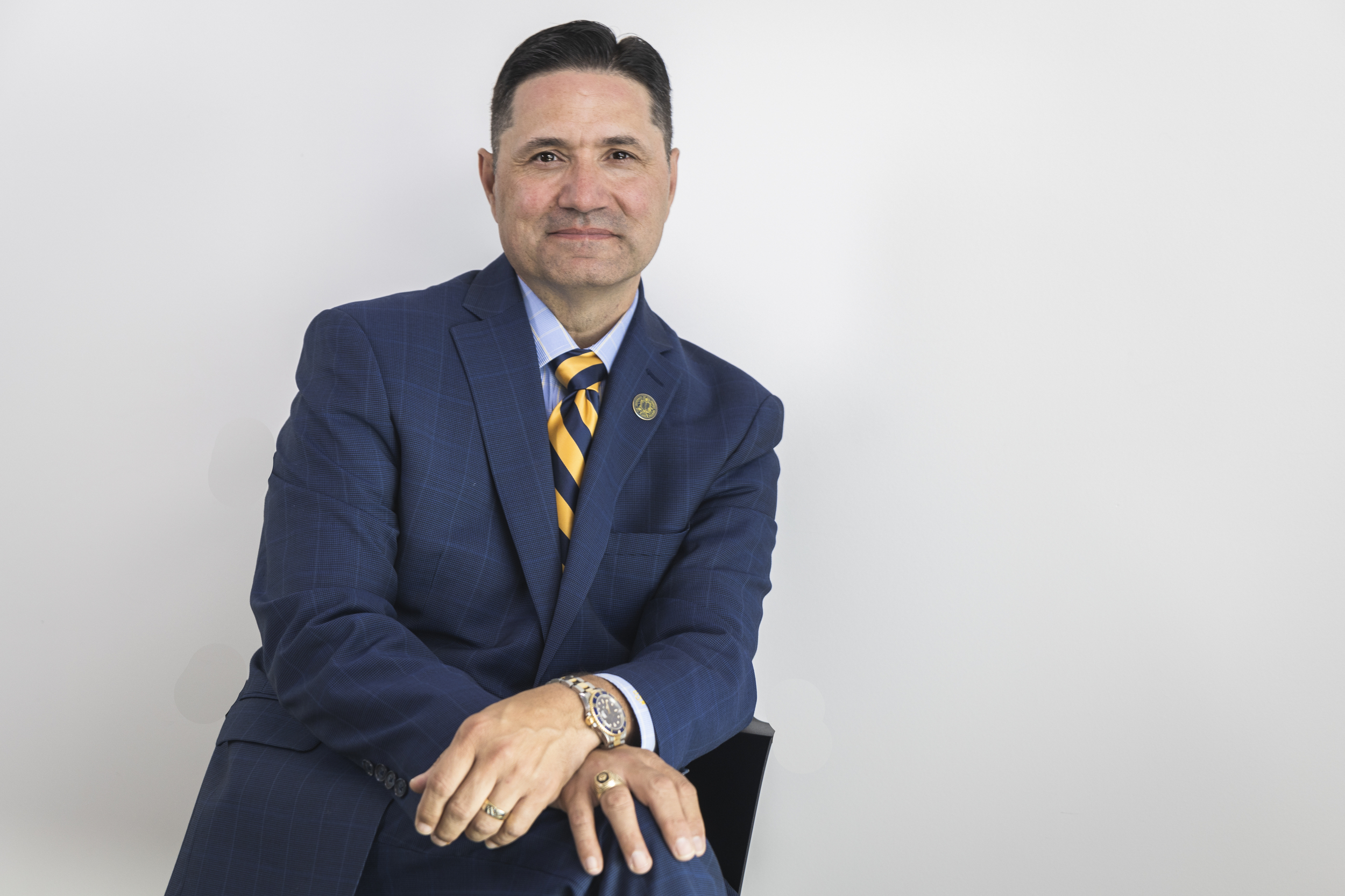 A man in a suit with a yellow and gold striped tie