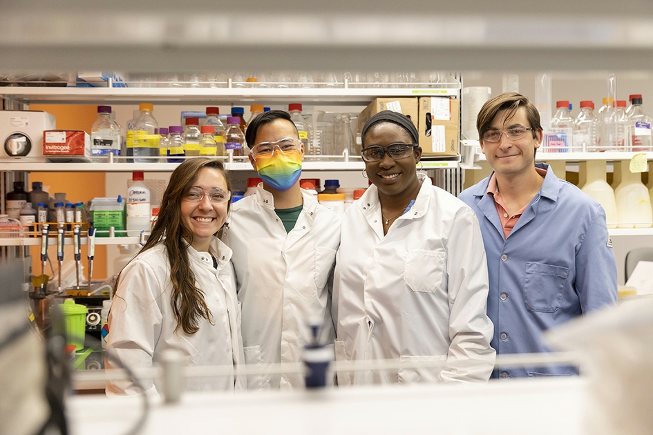 A group of students and a professor smiling in the lab