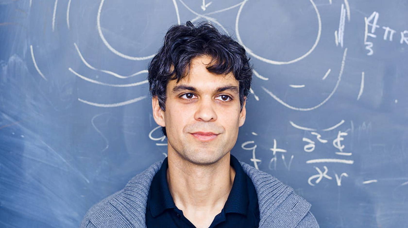 A person in front of a blackboard with equations and sketches