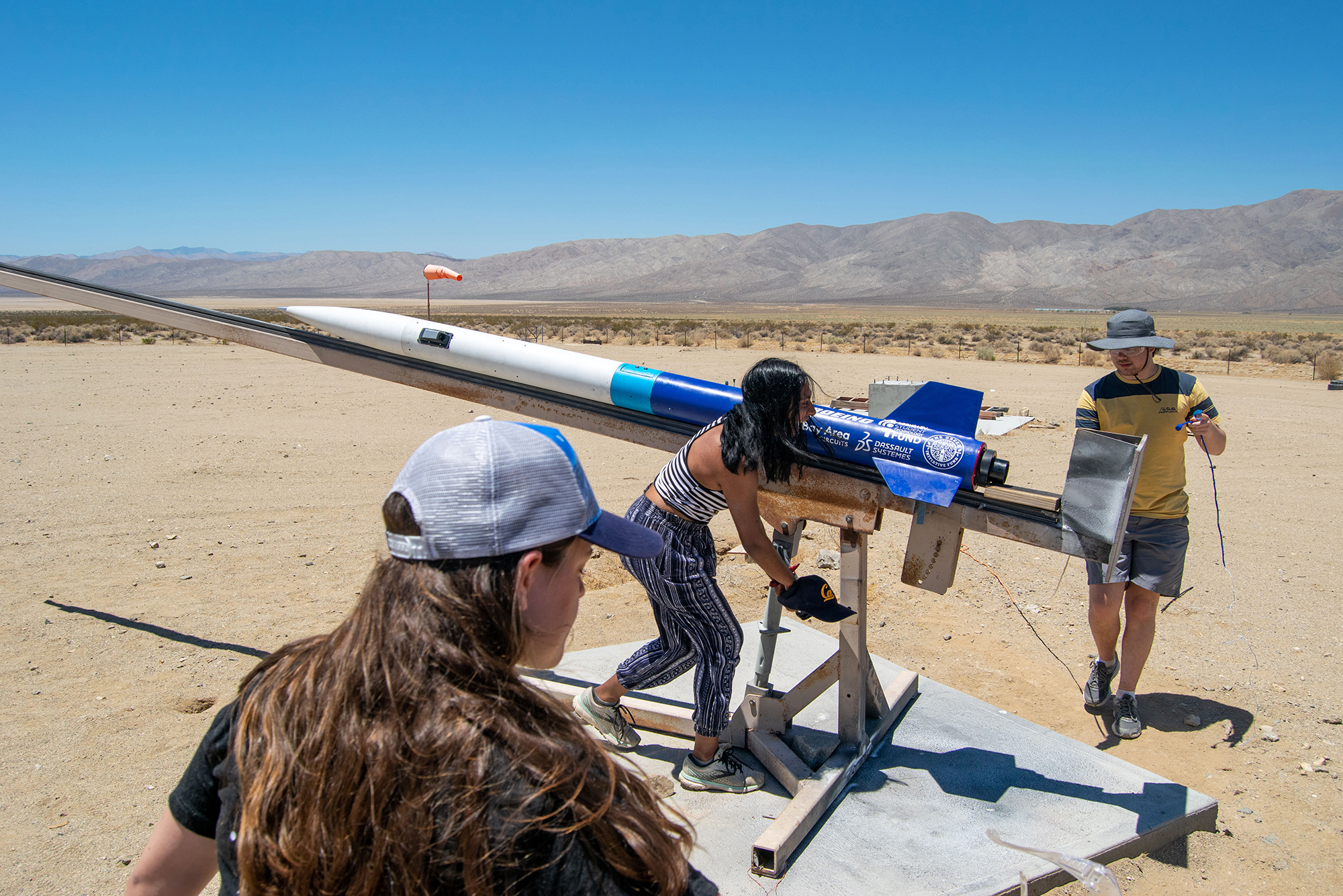 Students working on a rocket in a desert