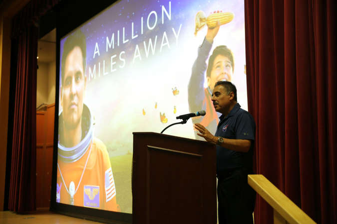 José Hernández gives remarks at a podium with a still of the film behind him